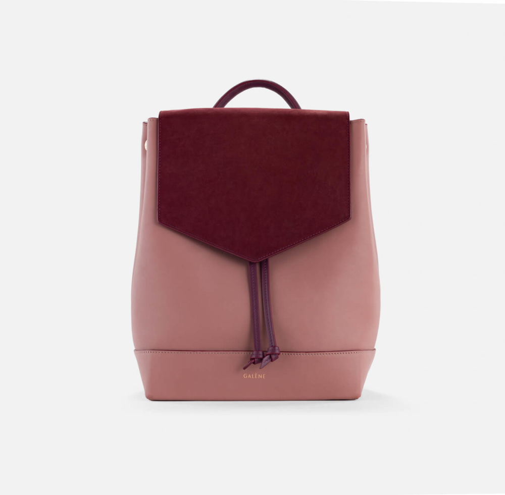 Un sac à dos Céline tendance rose et bordeaux au design soigné et doté d'un pompon, affiché sur un fond blanc uni.