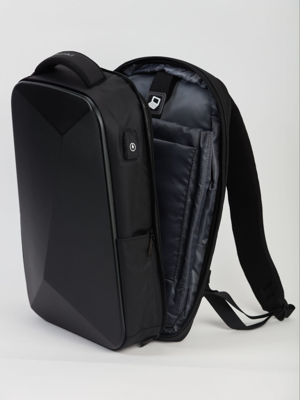 Un sac à dos noir élégant et structuré est partiellement ouvert, révélant un intérieur rembourré. Il est placé sur un simple fond clair.